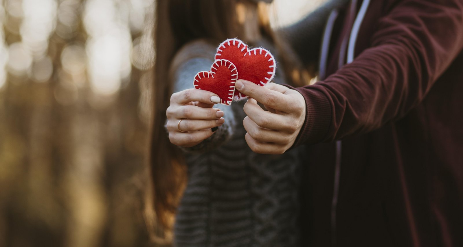 Una pareja de enamorados sostiene dos corazones rojos en sus manos por San Valentín